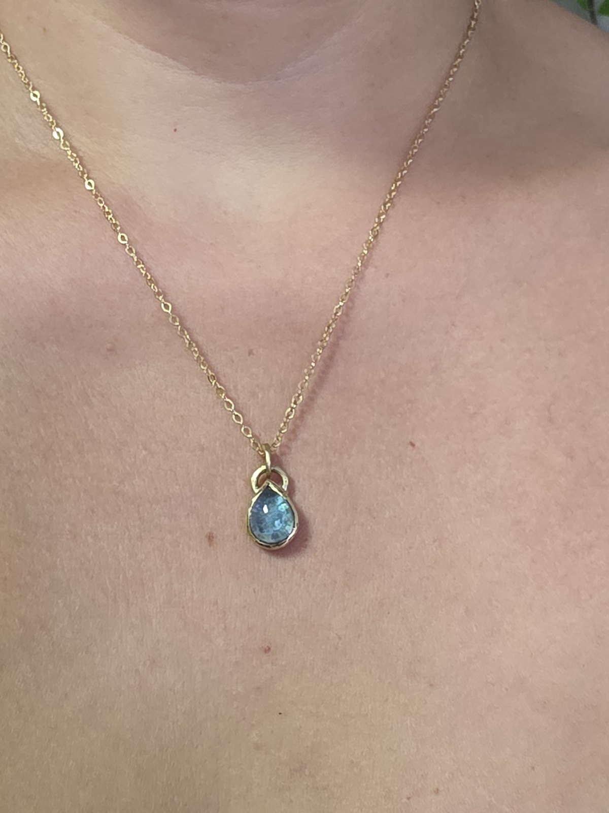 Colgante Alma Gota de oro 14k con cenizas 13 Colgante Alma Gota de oro 14k con cenizas y topacio azul, puesto en el cuello