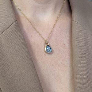 Colgante para cenizas de oro 14k Alma Gota con topacio azul, puesto en el cuello