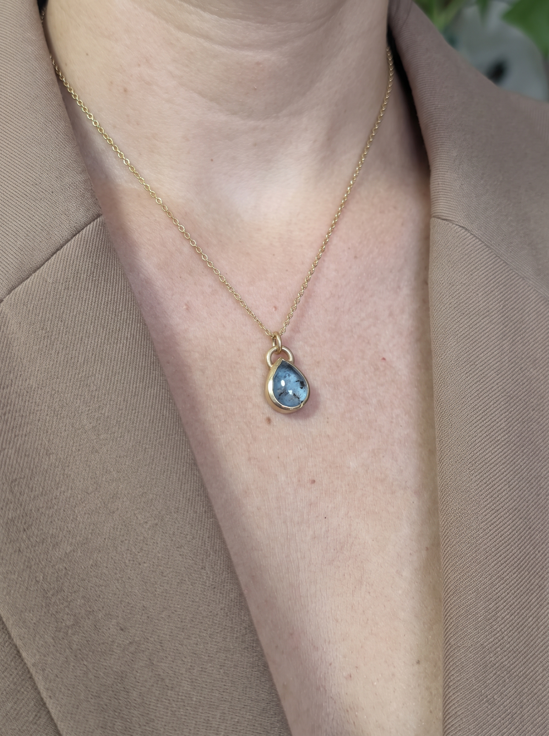 Colgante Alma Gota de oro 14k con cenizas 1 Colgante para cenizas de oro 14k Alma Gota con topacio azul, puesto en el cuello