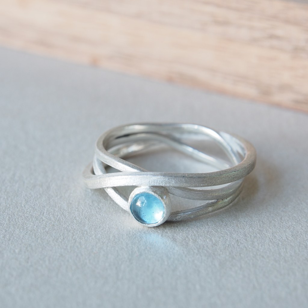 Anillo Etapas de plata con topacio azul, tres bandas