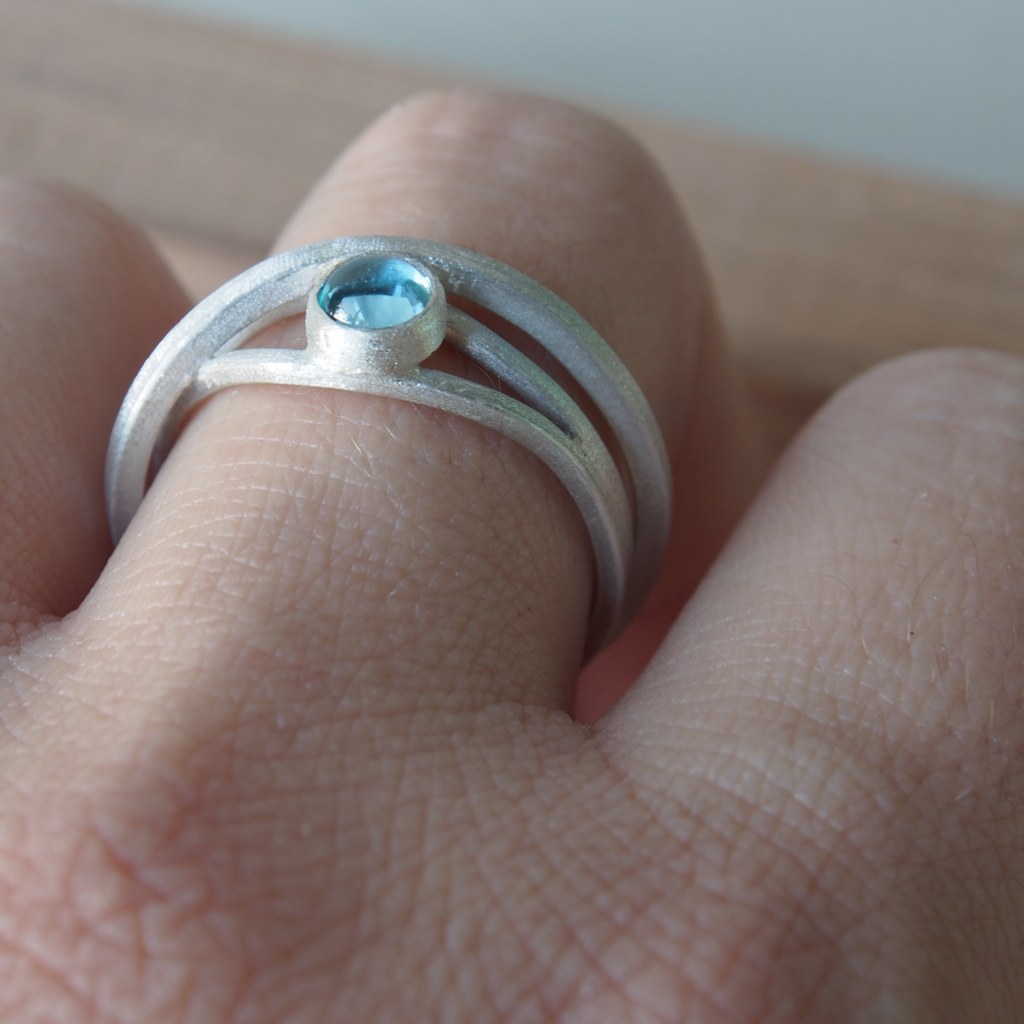 Anillo Etapas de plata con topacio azul puesto en la mano