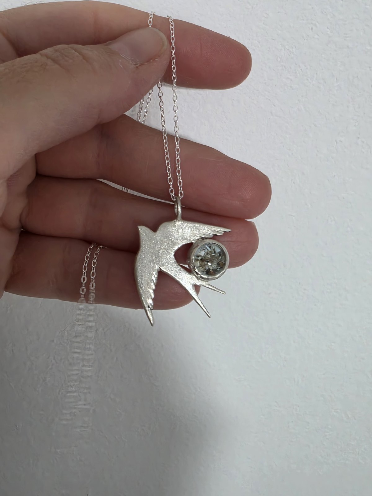Colgante Golondrina de plata con cenizas en la mano
