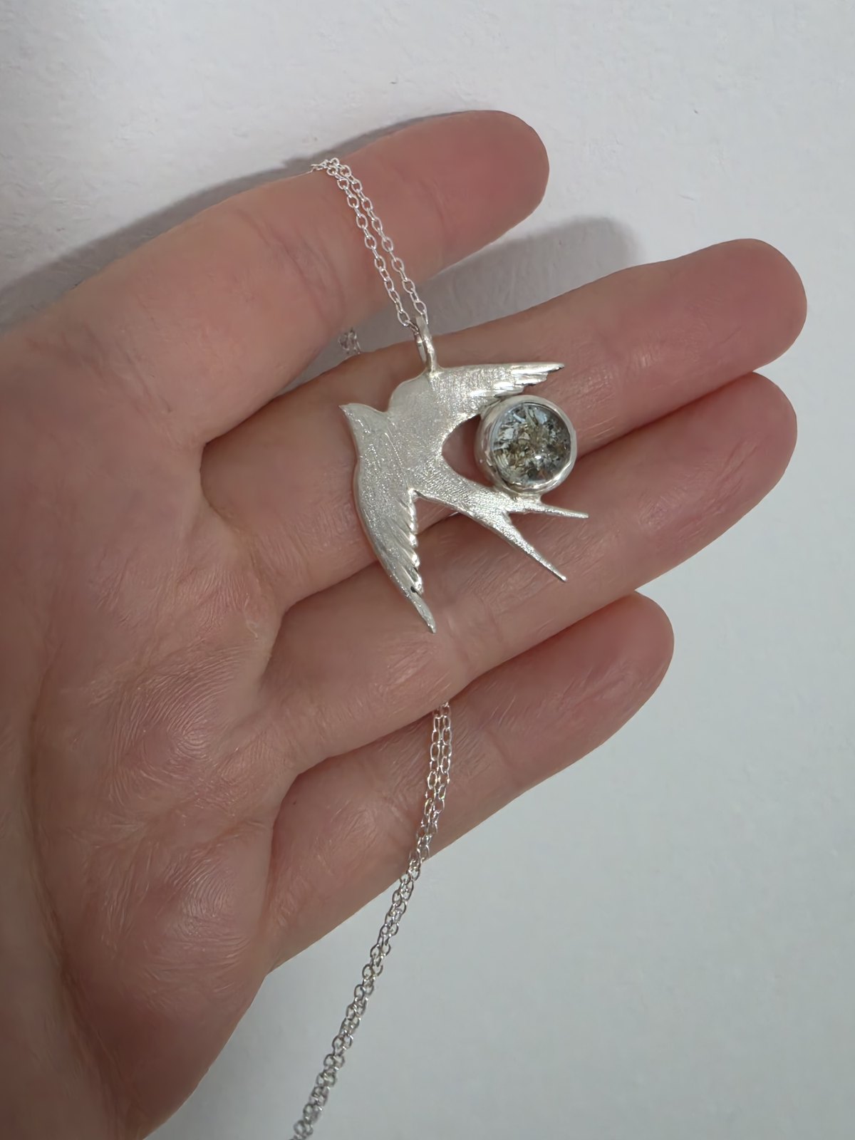 Colgante Golondrina de plata con cenizas sobre la mano